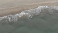 Aerial view of waves crashing on the shore with foam and undertow