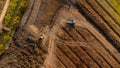 Aerial view of a wheel loader excavator with a backhoe loading sand onto a heavy earthmover at a construction site