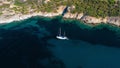 Aerial view of a white boat sailing in the sea near a cliffy shore