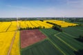 Aerial view Wind turbine on grassy yellow farm canola field against cloudy blue sky in rural area. Offshore windmill Royalty Free Stock Photo