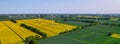 Aerial view Wind turbine on grassy yellow farm canola field against cloudy blue sky in rural area. Offshore windmill Royalty Free Stock Photo