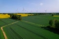 Aerial view Wind turbine on grassy yellow farm canola field against cloudy blue sky in rural area. Offshore windmill Royalty Free Stock Photo
