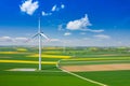 Aerial view of wind turbine. Rapeseed blooming. Windmills and yellow fields from above. Agricultural fields on a summer day. Royalty Free Stock Photo