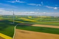 Aerial view of wind turbine. Rapeseed blooming. Windmills and yellow fields from above. Agricultural fields on a summer day. Royalty Free Stock Photo