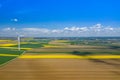 Aerial view of wind turbine. Rapeseed blooming. Windmills and yellow fields from above. Agricultural fields on a summer day. Royalty Free Stock Photo