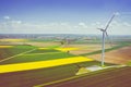 Aerial view of wind turbine. Rapeseed blooming. Windmills and yellow fields from above. Agricultural fields on a summer day. Royalty Free Stock Photo