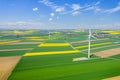 Aerial view of wind turbine. Rapeseed blooming. Windmills and yellow fields from above. Agricultural fields on a summer day. Royalty Free Stock Photo