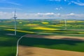 Aerial view of wind turbine. Rapeseed blooming. Windmills and yellow fields from above. Agricultural fields on a summer day. Royalty Free Stock Photo