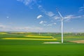 Aerial view of wind turbine. Rapeseed blooming. Windmills and yellow fields from above. Agricultural fields on a summer day. Royalty Free Stock Photo