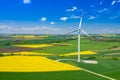 Aerial view of wind turbine. Rapeseed blooming. Windmills and yellow fields from above. Agricultural fields on a summer day. Royalty Free Stock Photo