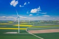 Aerial view of wind turbine. Rapeseed blooming. Windmills and yellow fields from above. Agricultural fields on a summer day. Royalty Free Stock Photo