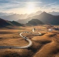 Aerial view of winding road in mountain pass, golden sunlight Royalty Free Stock Photo