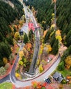 Aerial view of a winding rural road and train tracks, running through a dense forest in autumn Royalty Free Stock Photo