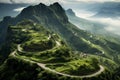 Aerial view of winding serpentine road in lush green summer mountains surrounded by mist and fog