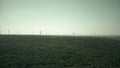 Aerial view of windmills and distant smoking stacks of a traditional power plant