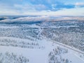 Aerial view of winter forest with frosty trees, rural road and village in Finland Royalty Free Stock Photo