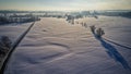 Aerial view of a winter landscape with a sunset casting a glow over a snow-covered field