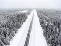 Aerial view at wintry road during snowy storm, highway in northern forest Royalty Free Stock Photo