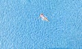 Aerial view with woman in bikini sunbathing as laying on swim ring as blue sea water