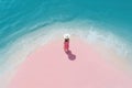 Aerial view of woman with pink skirt and white hat stay on sandy beach near sea with waves Royalty Free Stock Photo