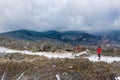 Aerial view on a woman runner in a red sweatshirt stands on a mountain trail ready to run.