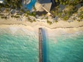 Aerial view of a wooden bridge on the sea. White sandy beach, palm trees on the shore, the roofs of tall buildings and small Royalty Free Stock Photo