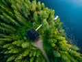 Aerial view of wooden cottage in green forest by the blue lake in rural summer Finland