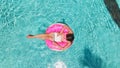 Aerial view of a young brunette woman swimming on an inflatable big donut with a laptop in a transparent turquoise pool. Royalty Free Stock Photo