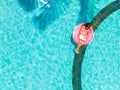 Aerial view of a young brunette woman swimming on an inflatable big donut with a laptop in a transparent turquoise pool. Royalty Free Stock Photo