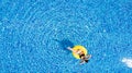 Aerial view of young brunette woman swimming on the inflatable big yellow ring in pool Royalty Free Stock Photo