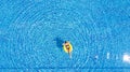 Aerial view of young brunette woman swimming on the inflatable big yellow ring in pool Royalty Free Stock Photo