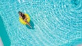 Aerial view of young sexy woman in bikini swimming on the inflatable big yellow ring in pool Royalty Free Stock Photo