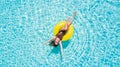 Aerial view of young sexy woman in bikini swimming on the inflatable big yellow ring in pool Royalty Free Stock Photo