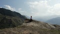 Aerial view of a young woman sitting on the top of epic cliff rock. Action. Concept of freedom and adventure, travelling Royalty Free Stock Photo