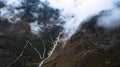 Aerial view on zig zag mountainous road through the valley next to the river and clouds Royalty Free Stock Photo