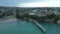 Aerial view zooming out of the shore, seaside houses and a dock at Murrays bay, Auckland