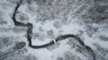 Aerial winter landscape. Tiny river between snowy forest