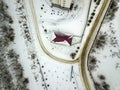 Aerial winter top view of house roof on fenced property, snowy field and dirty road