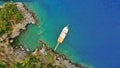 Aerial. Yacht boat stopped in a blue sea bay and man swims in sea. Top view.