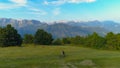 AERIAL: Young man on mountain biking trip crosses a vast meadow in mountains. Royalty Free Stock Photo