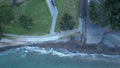 Aerial zooming out the shore and the beach of Murrays Bay, Auckland, with foamy waves on the shore