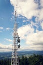 Aerials and transmitters on telecommunication tower with mountains in background Royalty Free Stock Photo