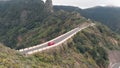 Aero view - a lonely car drives through a narrow and dangerous road high in the green mountains. Serpentine at high Royalty Free Stock Photo