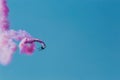 Aerobatic plane leaving a pink smoke trail in the blue sky. Royalty Free Stock Photo