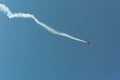 Aerobatic plane leaving a white smoke trail in the blue sky. Royalty Free Stock Photo