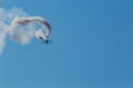 Aerobatic plane leaving a white smoke trail in the blue sky. Royalty Free Stock Photo