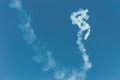 Aerobatic plane leaving a white smoke trail in the blue sky. Royalty Free Stock Photo