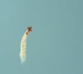 Aerobatic plane leaving a white smoke trail in the blue sky. Royalty Free Stock Photo