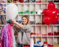 a woman inflates of helium from a white balloon.