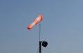 The aerodrome white-red cone-wind indicator flutters against the blue sky